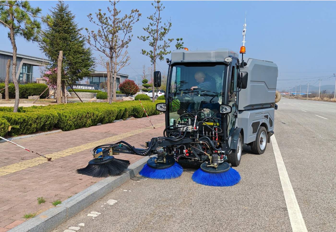Road sweeper elektrik membersihkan jalan dengan tiga sikat